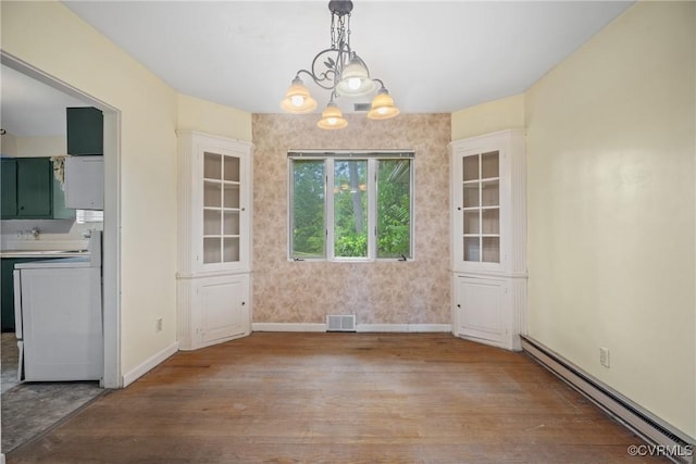 unfurnished dining area with an inviting chandelier, light wood-type flooring, and a baseboard heating unit