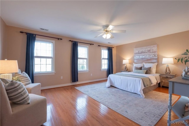 bedroom featuring light wood finished floors, baseboards, visible vents, and a ceiling fan