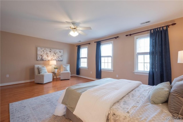 bedroom with baseboards, multiple windows, visible vents, and light wood-style floors