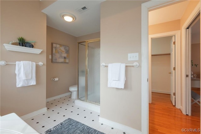 bathroom featuring toilet, a stall shower, visible vents, and baseboards