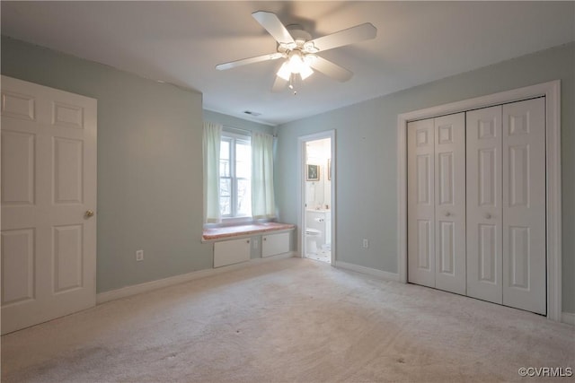 unfurnished bedroom with light carpet, baseboards, a ceiling fan, connected bathroom, and a closet