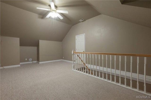 additional living space with baseboards, visible vents, light colored carpet, ceiling fan, and vaulted ceiling