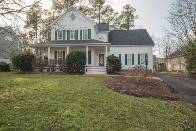 view of front of house featuring driveway, covered porch, a shingled roof, and a front lawn