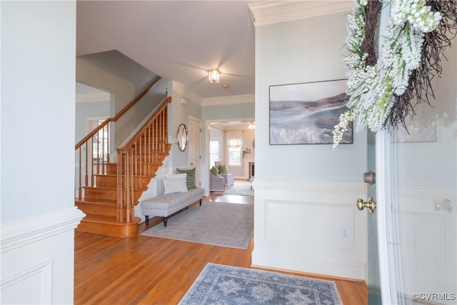 foyer with stairs, wood finished floors, and crown molding