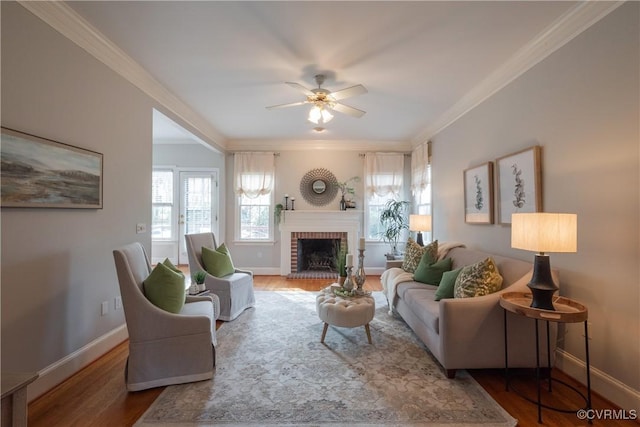 living area with baseboards, a fireplace, ornamental molding, and wood finished floors