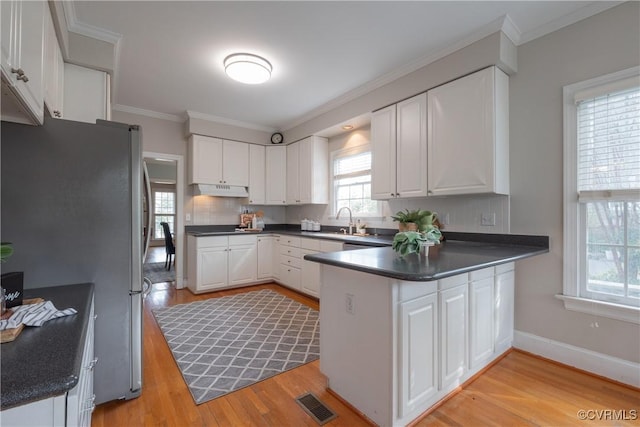 kitchen featuring dark countertops, light wood-style floors, white cabinets, and freestanding refrigerator