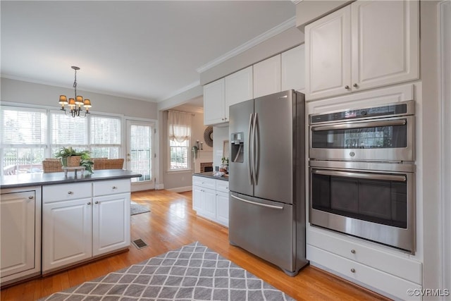 kitchen with appliances with stainless steel finishes, dark countertops, white cabinetry, and crown molding