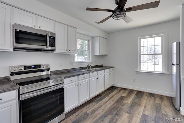 kitchen with white cabinetry, stainless steel appliances, sink, ceiling fan, and dark hardwood / wood-style floors