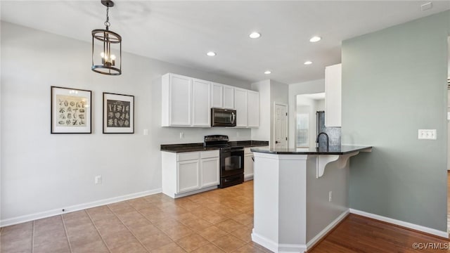 kitchen with electric range, kitchen peninsula, decorative light fixtures, white cabinets, and a kitchen breakfast bar