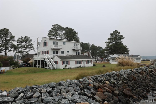 back of property featuring a balcony and a yard