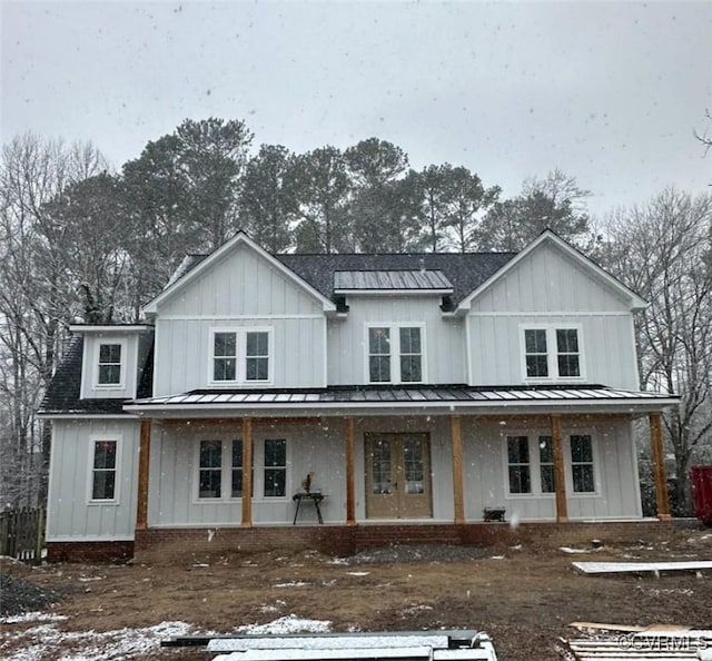 modern farmhouse with a standing seam roof, metal roof, board and batten siding, and covered porch