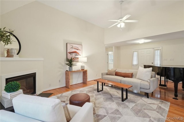 living room with ceiling fan, high vaulted ceiling, and light hardwood / wood-style floors