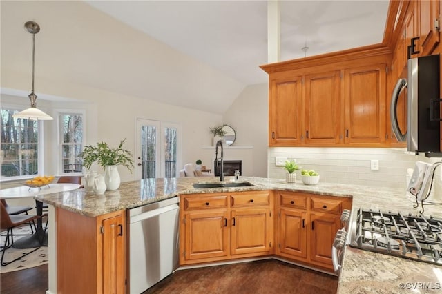 kitchen featuring kitchen peninsula, hanging light fixtures, sink, vaulted ceiling, and appliances with stainless steel finishes