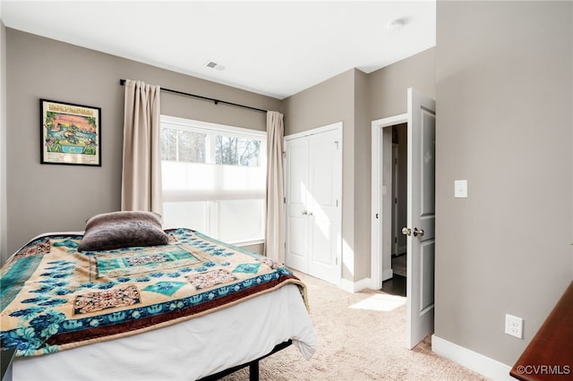 bedroom with light carpet, baseboards, visible vents, and a closet