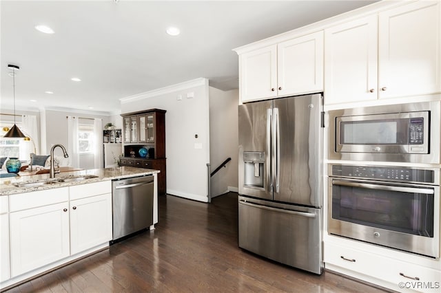 kitchen with crown molding, stainless steel appliances, white cabinetry, a sink, and light stone countertops