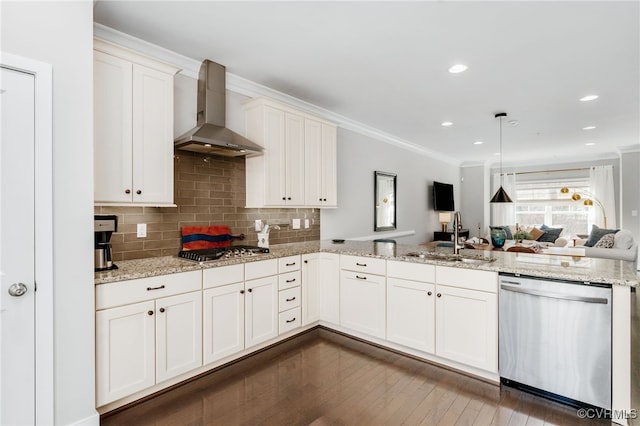 kitchen with crown molding, stainless steel appliances, a sink, wall chimney range hood, and a peninsula