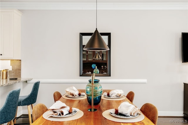 dining room with crown molding, wood finished floors, and baseboards