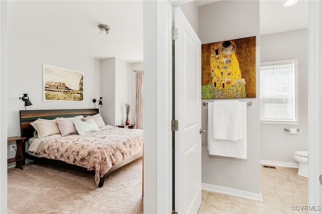 bedroom with visible vents, connected bathroom, baseboards, and light tile patterned floors