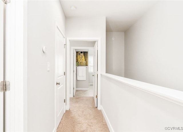 hall with light colored carpet and baseboards