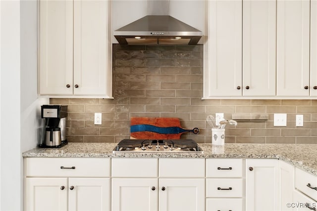 kitchen featuring wall chimney exhaust hood, tasteful backsplash, and white cabinets