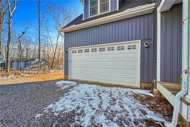 snow covered garage featuring driveway