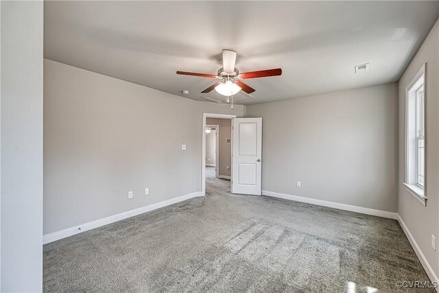 carpeted empty room with a ceiling fan, visible vents, and baseboards