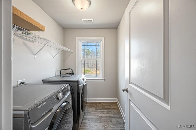 laundry room featuring baseboards, wood finished floors, washing machine and dryer, and laundry area