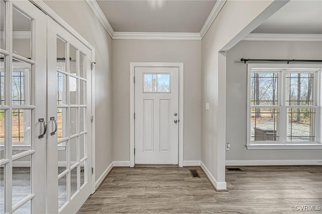 foyer featuring french doors, wood finished floors, a healthy amount of sunlight, and ornamental molding