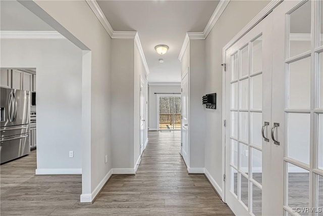 hallway with baseboards, wood finished floors, and ornamental molding