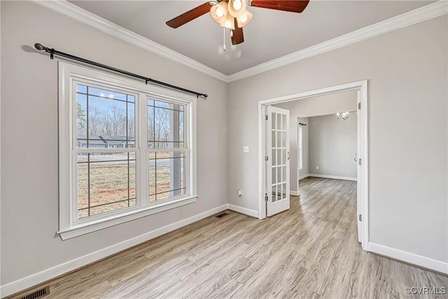 empty room with crown molding, baseboards, visible vents, and light wood finished floors