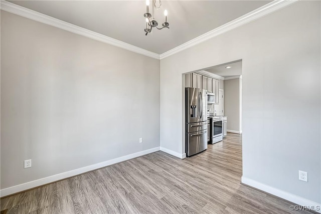 unfurnished dining area with crown molding, a notable chandelier, wood finished floors, and baseboards