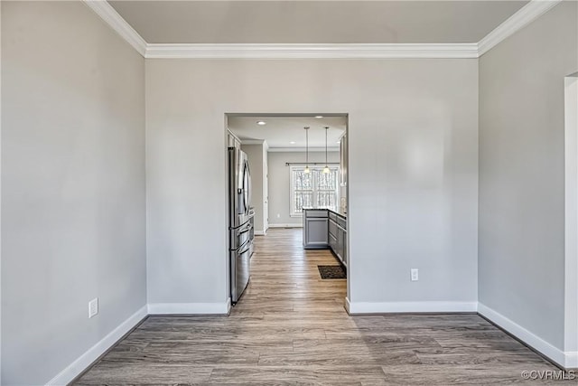 spare room featuring a chandelier, crown molding, baseboards, and wood finished floors