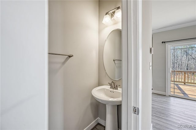 bathroom featuring baseboards, wood finished floors, and ornamental molding