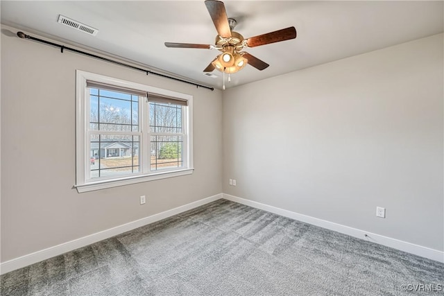 carpeted spare room with visible vents, a ceiling fan, and baseboards