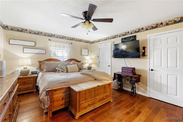 bedroom with dark wood-style flooring, ceiling fan, a textured ceiling, and baseboards