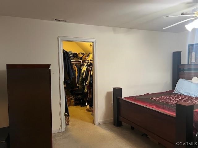 bedroom with light carpet, visible vents, a ceiling fan, a spacious closet, and a closet