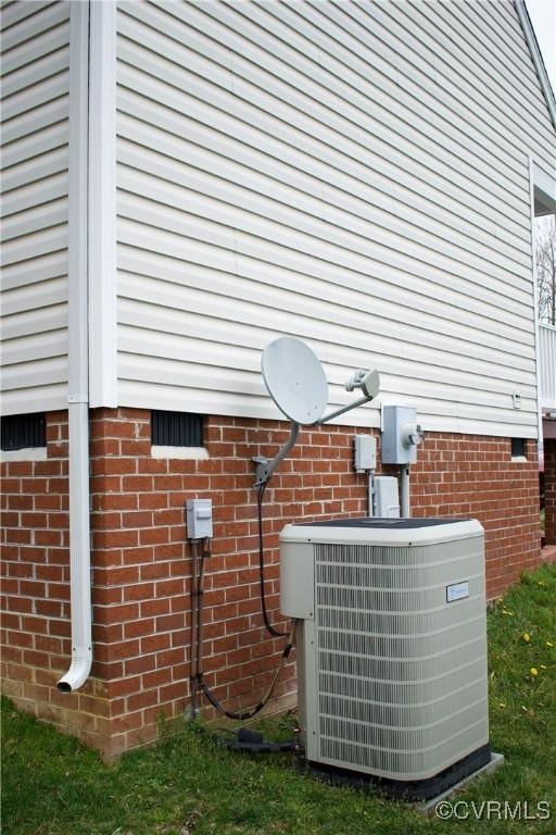 exterior details with brick siding, electric meter, crawl space, and cooling unit