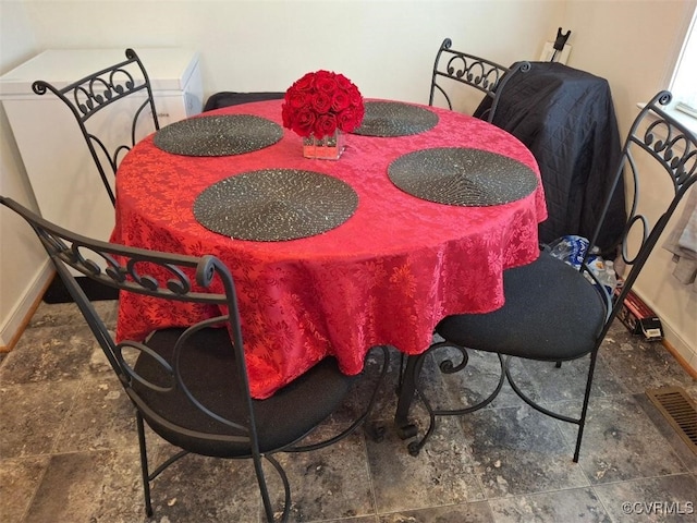 dining space featuring baseboards, stone finish flooring, and visible vents