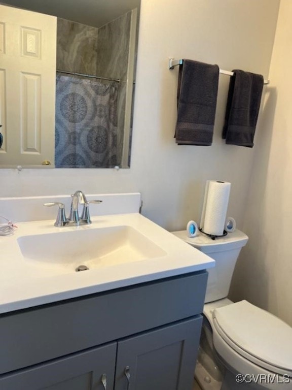 bathroom featuring vanity, curtained shower, and toilet