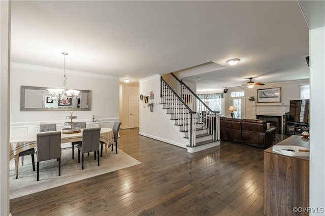 dining area with dark wood-type flooring, a fireplace, crown molding, and stairway