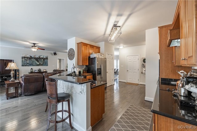 kitchen featuring dark wood finished floors, dark countertops, open floor plan, a sink, and stainless steel fridge