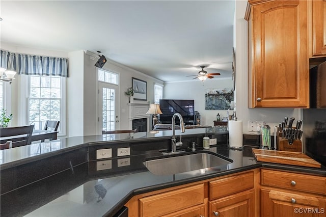 kitchen featuring ceiling fan, brown cabinets, open floor plan, a fireplace, and a sink