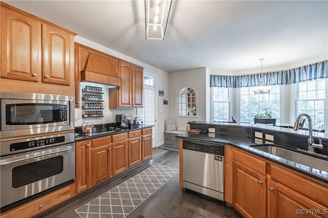 kitchen with dark countertops, dark wood-style floors, stainless steel appliances, and a sink