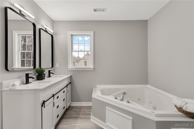 bathroom with a washtub, vanity, and wood-type flooring