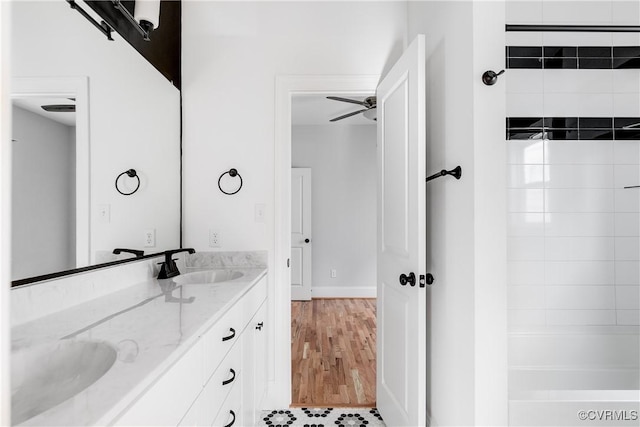 full bathroom with double vanity, a shower, a ceiling fan, wood finished floors, and a sink