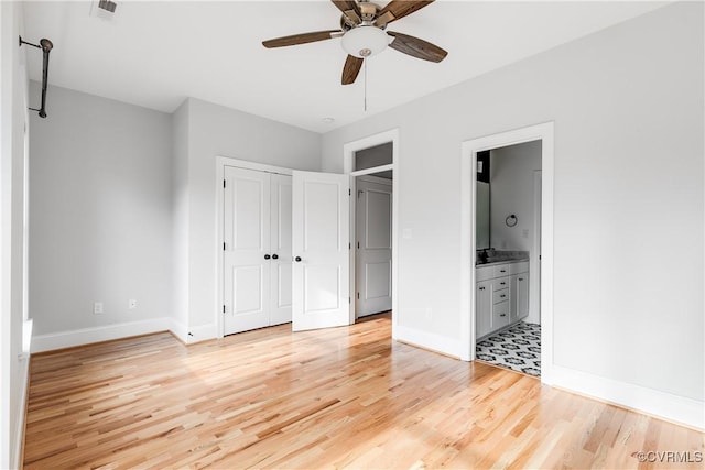 unfurnished bedroom featuring a closet, visible vents, ensuite bathroom, light wood-style floors, and baseboards