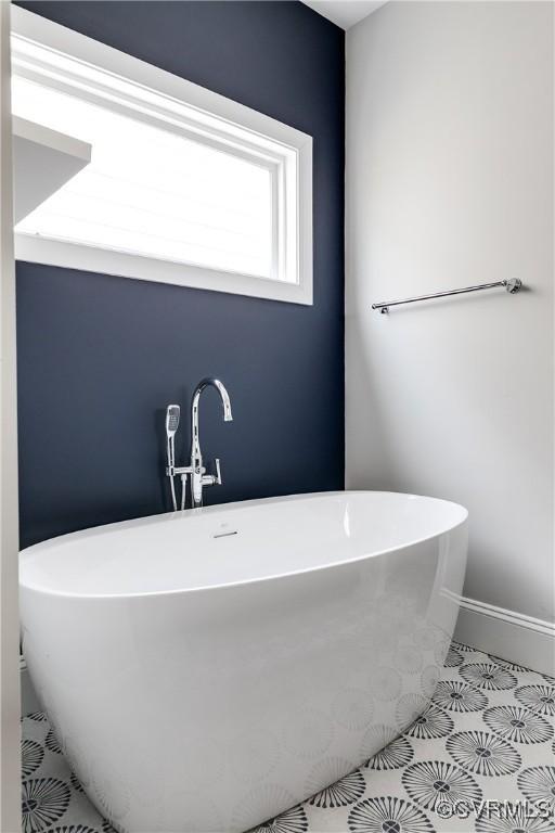 bathroom featuring tile patterned flooring, a soaking tub, and baseboards