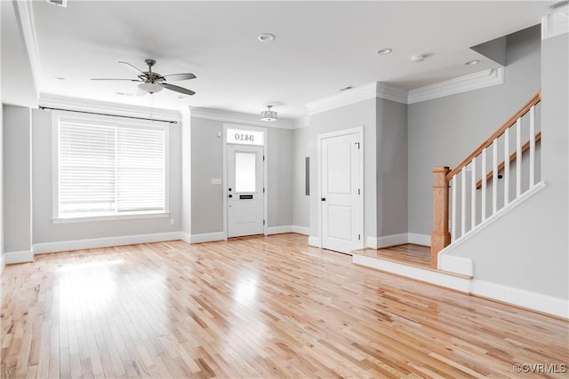 foyer featuring ceiling fan, baseboards, stairs, ornamental molding, and light wood-type flooring