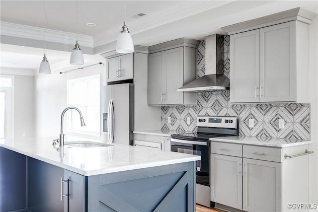 kitchen featuring a sink, ornamental molding, wall chimney range hood, appliances with stainless steel finishes, and decorative light fixtures