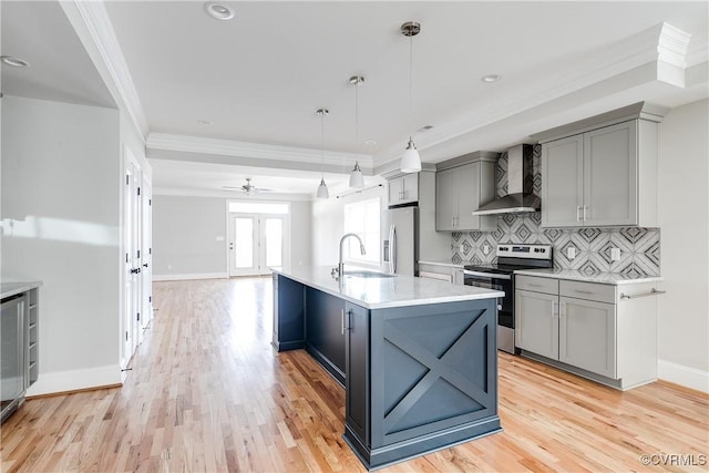 kitchen featuring appliances with stainless steel finishes, light countertops, a sink, and wall chimney exhaust hood